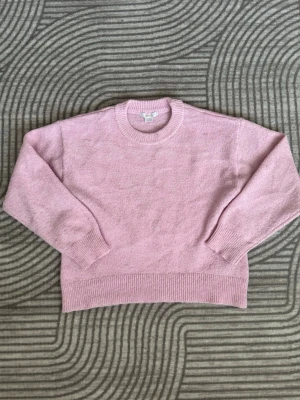 Nu Ljusrosa stickad tröja Gina tricot  - Mysig ljusrosa stickad tröja med rund halsringning och ribbade muddar vid ärmslut och nederkant. Tröjan har en avslappnad passform och är perfekt för lager på lager. 