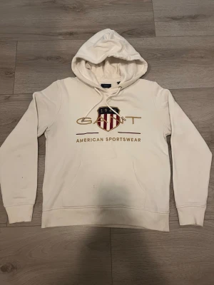 Gant Hoodie - Säljer en vit hoodie från Gant men att den är lite fläckig på magen och armarna då ni kan se på slutet av bilderna . Jag har inte försökt bli av med fläcken men inte säkert på att det ens går 