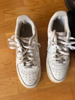 Vita klassiska sneakers med snörning - Snygga vita sneakers med lågt skaft och klassisk design. Skorna har perforerade detaljer på tån för ventilation, vit sula och snörning framtill. Perfekta för en clean och stilren look till vardags. Materialet är syntet och textil.