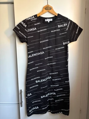 Ny, svart klänning med text på - Helt ny klänning med vit text på. Korta ärmar. 