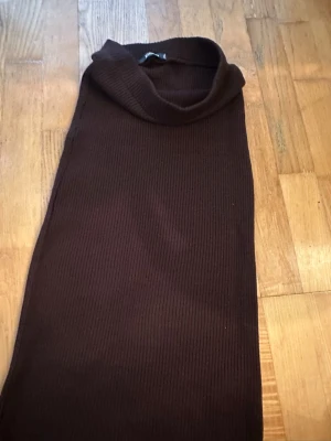 Mörkbrun ribbad midikjol - Säljer en mörkbrun midikjol med ribbad struktur. Kjolen har en enkel och stilren design i stretchigt material som ger en snygg passform. Perfekt för dig som gillar minimalistiska plagg med en twist.