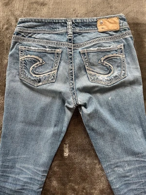 Blå bootcut jeans med lågmidja - Snygga bootcut jeans från silver med fina detaljer! Midjemått-37cm innerbenslöngd- 82cm