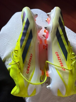 Gula Adidas Crazyfast fotbollsskor - Säljer ett par grymma Adidas Crazyfast fotbollsskor i neon-gult med svarta detaljer och vita sulor. Skorna har snörning, låg profil och lätta material för maxad speed på planen. Perfekta för dig som vill sticka ut och spela snabbt.
