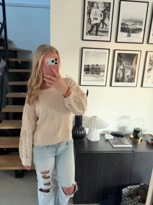 Beige tröja med pärlärmar - Snygg beige stickad tröja med paljetter på armarna. Använd några gånger. Köpt ny för ca 350kr och säljer för 130kr. Står onesize men känns som en S.