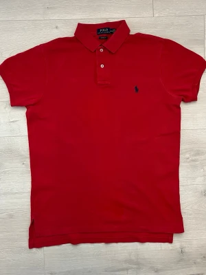 Ralph lauren pike - Säljer en klassisk röd piké från Ralph Lauren. Ett tidlöst plagg som passar perfekt till både vardag och lite mer uppklädda tillfällen.  • Storlek: M • Färg: Röd • Skick: Mycket fint skick • Klassisk passform med broderad Ralph Lauren-logga • Mjuk och bekväm kvalitet • Perfekt att matcha med jeans, shorts eller chinos  En stilren och lättmatchad piké i mycket fint skick. Hör gärna av dig vid frågor eller om du vill ha fler bilder! 👍