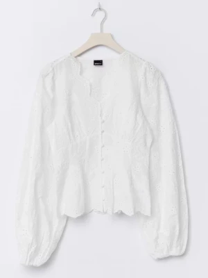Vit broderad blus med knappar - Söt vit blus med broderade detaljer och knappar framtill. Blusen har långärmade puffärmar och en lätt vågig kant vid halsringningen. Tillverkad i ett tunt, luftigt tyg som ger en romantisk känsla.