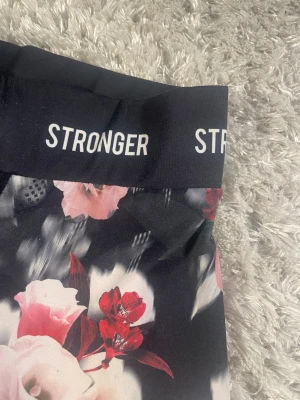 Blommiga leggings från Stronger - Snygga leggings från Stronger med logotyp i vitt på linningen. Stretchigt material som sitter tight och är perfekt för träning. Supersnygg design! Hör gärna av dig om du har någon fråga💕💕