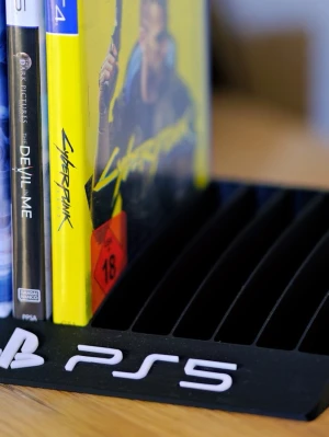 PS5 och PS4 spelställ i plast - Snyggt spelställ för PS5 och PS4 spel, tillverkat i plast med svart och vit färg. Har PS5-logga framtill och plats för flera spel. Perfekt för att organisera dina favoritspel på ett stilrent sätt i gamingrummet.