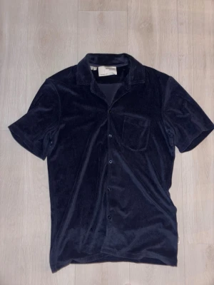 Mörkblå kortärmad skjorta från Selected Homme - Snygg mörkblå skjorta från Selected Homme i mjukt material. Skjortan har korta ärmar, klassisk krage, bröstficka och knäppning framtill. Perfekt för en stilren och avslappnad look.