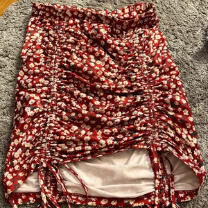 Kjol - Super fin röd kjol med blommor på, du kan justera längden på den och det sitter väldigt fint om kroppen! köparen står för frakten! Kom privat om du är intresserad och var inte rädd för att fråga om du undrar något!!💕