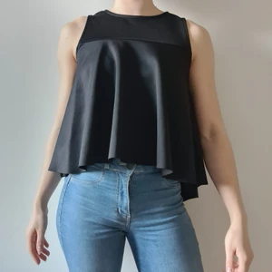 Svart festtopp Gina Tricot, stl. M - En svart skön finare topp, i stretchigt material som passar både på kontoret och till fest. Den är kortare framtill och längre bktill, i nedanstycket är tyget volanger. Från Gina Tricot. Frakt tillkommer.