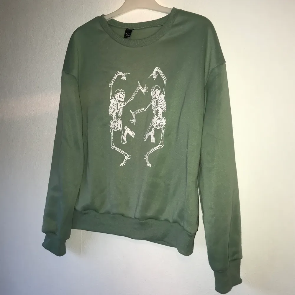 Ljus grön sweatshirt med två vita dansande skelett på från Shein. Knappt använd, ser helt ny ut! storlek M men passar XS och S. Köparen står för frakt!. Hoodies.