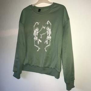 Ljus grön sweatshirt med två vita dansande skelett på från Shein. Knappt använd, ser helt ny ut! storlek M men passar XS och S. Köparen står för frakt!