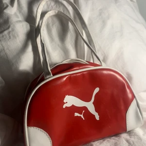 Puma axelväska - Liten röd söt puma axelväska, köpt här på plick och nästan aldrig använd. Alltså i fint skick❤️ måtten är 21cm på längden och 13cm på höjden 💓 Skriv privat för frågor eller mer bilder 💋