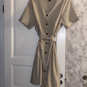 Klänning  - Beige klänning, men knappar och knyte i midjan 