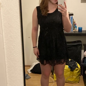 Kortklänning  - Detta är en klänning från Amelia. Den är svart och har ett blommönstrat tyg. Den är för kort att ha bara som klänning, så man kan ha Jeans under. Den är oanvänd o har inga defekter. Storlek M. Nån slags lapp hänger på.