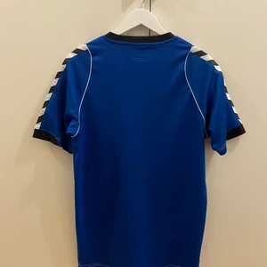 Träningströja Hummel, Strl. L - Blå träningströja från Hummel, Strl. L.  Bra skick, men finns en söm där bak som börjat gå upp (se sista bilden). 