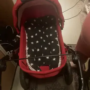 En röd barnvagn av märket first Wheel en amningskudde och ett babynest till salu paketpris