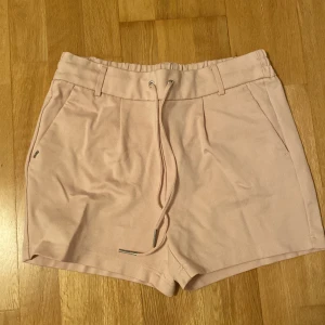 Kostym shorts  - Rosa shorts som ser ut som kostymbyxor. Resår med band i midjan. Storlek 38. 