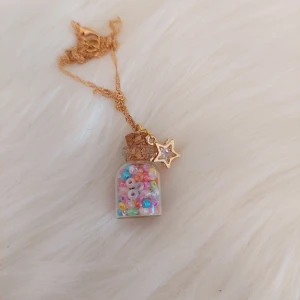 Handgjort halsband  - Handgjort halsband. Liten flaska fylld med färgglada seabeeds pärlor och en hängande stjärna. Halsbandet är 42 cm långt.