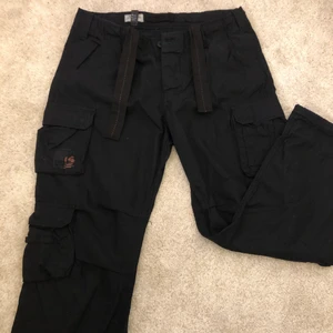 Vintage cargo i svart - Vintage cargo unisex byxor i svart, likadana som jean vintage i strl XL men passar mer M-L då dom ej är stretchiga! Påminner om brandit. Oanvända och har band för att spänna i midjan, är själv en strl XS/S och har dessa i M. Sedda på pinterest. 