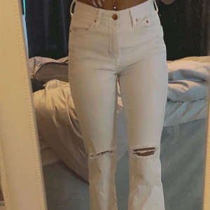 H&M jeans  - Högmidjade, vita bootcut jeans slitna vid knäna 