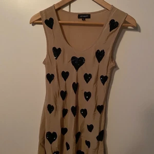 Snygg klänning/tunika i silke - Fin tunika/klänning med svarta paljetthjärtan. Från Smooph. Färgen något ljusare än bilderna, mer som sista bilden. Storlek S. Aldrig använd och i nyskick, jag hittar ingenting att anmärka på förutom att den är lite skrynklig. Material enligt bild (silke).