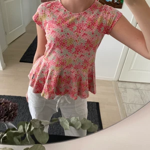 Blommig volang t-shirt  - Säljer en jättesöt rosa blommig volang topp/t-shirt från polarn o.pyret, användes mest när jag var yngre men tyvärr har den ej kommit till användning längre🌙 jätteskönt material och jättefin nu till sommaren 🌸