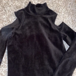 Polotröja Zara - Svart polotröja från Zara, jättefin att ha som en fest tröja till kjol eller ett par byxor. Tröjan är öppen på sidorna vid axeln vilket gör den lite speciell. 