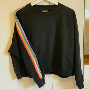 Oversized sweatshirt från Monki  - Jätteskön oversized och croppad svart tröja från Monki med lite glittrigt regnbågsmönster längs armarna. Storlek S men som sagt oversized, aldrig använd! Köparen står för frakten