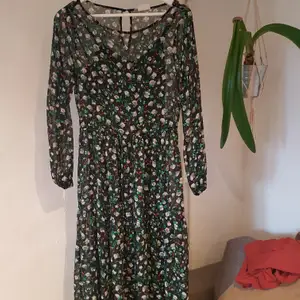 Black see through dress with green, white and orange flowers. The dress has a drawstring at the waist and a black slipdress attatched as a base layer. It's a little long on me (I'm 158cm) that's why I'm selling. 