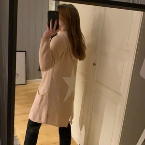 Kofta med stjärna Strl S - En längre kofta med stjärna på ryggen, sitter som på bilden. Den är i använt skikt men ser fortfarande fin ut. Strl S men vet ej vilket märke. OBS! Köparen står för frakten.