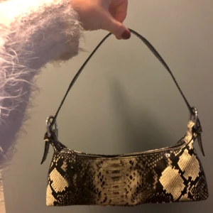 Ormskinnsmönstraf handväska från Monki - Nyskick!! Axelbandet kan justeras något men sitter väldigt tätt under armen. Något mer ”gul” än vad som syns på bilderna (aka snyggare😛)