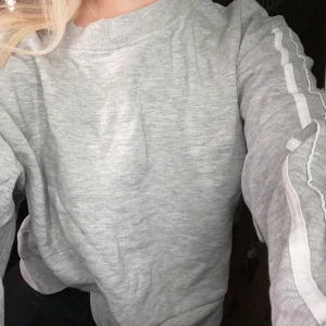 Grå sweatshirt med vita sträck - Denna gråa sweatshirt är fram Hm i storlek S men skulle även passa en M då den är lite oversized. Väldigt fin och skön:)