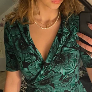 Grön Omlott Klänning  - Säljer denna cool omlottklänningen med detta snygga tryck💚💚 Den är i storlek M och sitter som en M. Denna klänning passar perfekt till varma sommardagar då materialet är luftigt och skönt! Fråga för fler bilder eller frågor:) Köparen står för frakt📦📦