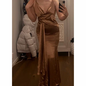 Balklänning - Säljer en balklänning jag köpte för snart 3 år sedan till balen i 9an men använde aldrig då jag hittade en annan. Från Asos köpte för drygt 700 kr. Aldrig använd. Den är för liten för mig nu då jag vuxit så sitter för tajt vid låren och går inte att stänga helt bak, därför säljer jag! Rostfärgad och glänser superfint i solen! 