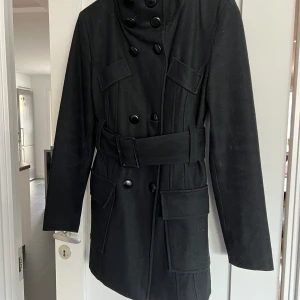 Kappa med bälte från Tessie - Snygg svart kappa som endast är använd någon säsong
