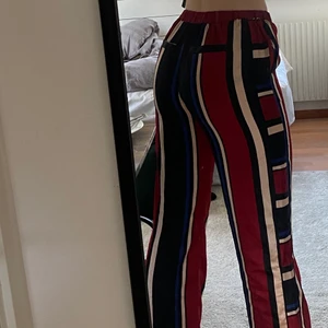 Randiga byxor  - Randiga multi colored byxor med silkes intryck, köpt från NA-KD - säljer pga: för korta (jag är ca. 182 cm) 