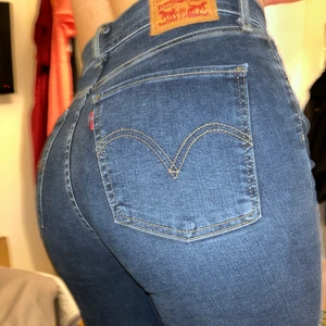 Levis Jeans - Levis jeans som knappt är ancända i mörkare blå. Nypris 1150kr nyskick och mycket fina, avklippta (original) nertill. Hellängd. Sitter tight i midjan, passar kurvig kropp bra. Högmidjade. Sitter som jeans i storlek S