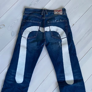 Äkta Evisu jeans  - Äkta evisu jeans köpte på en secondhand affär i Spanien. Sjukt snygga och sköna. Trycket är handmålat och eftersom dom är vintage har dom lite sprickor osv. Sitter så sjukt bra. Är 182cm och dom är raka/ baggy, speciellt på någon kortare.                            W: 28 L:36 