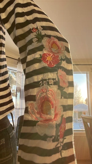 Randig tröja med blommiga brodyrer - En randig tröja med vida armar och brodyrsydda blommor på armarna. Tröjan är ifrån HM men jätte fin. Säljer den nu då den blivit för kort för mig. Det är XS och jag är drygt 170 lång. Tröjan har inga slitage så som hål eller annat. 