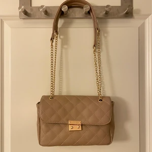Beige/guld väska  - En liten beige väska med gulddetaljer och kedja med justerbara band som tyvärr inte kommer till användning. 65 kr inklusive frakt.🥰 SE MIN PROFIL FÖR FLER VÄSKOR ALTERNATIVT SAMFRAKT!