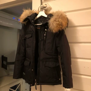 Hollies livingo jacka - Jättefin vinterjacka från Hollies. Använd en vinter men hänger mest i garderoben nu för tiden. Har en liten defekt precis nedanför luvan som inte märks av när man har på sig jackan men är övrigt i väldigt fint skick. Nypris 4499kr.