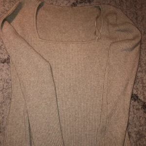 Ribbad tröja - En jättefin beige ribbad tröja med en rektangulär form runt halsen. Väldigt skön och stretchig. Kan passa mellan strl S-L beroende på hur men vill att den ska sitta.Använd 1-2 ggr, annars är den i nyskick. 