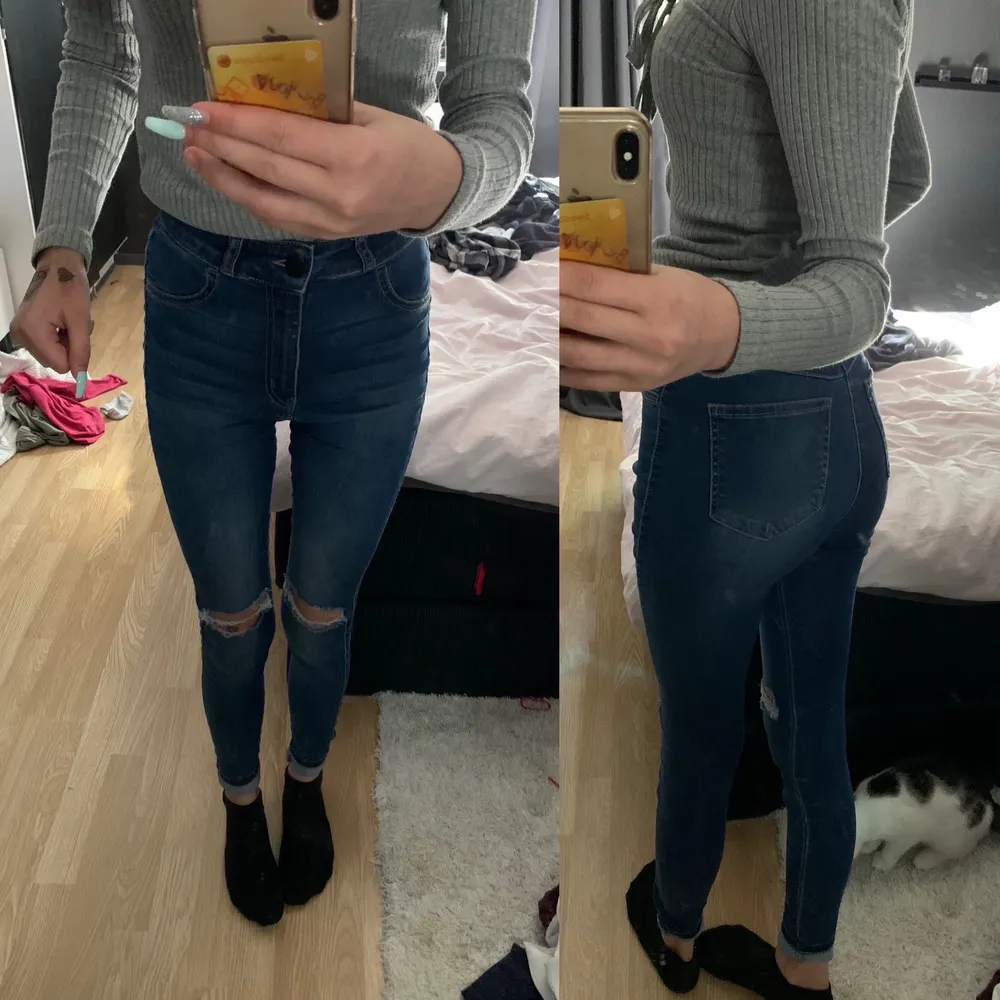 Ett par blåa högmidjade jeans med hål i knäna. Jeans & Byxor.