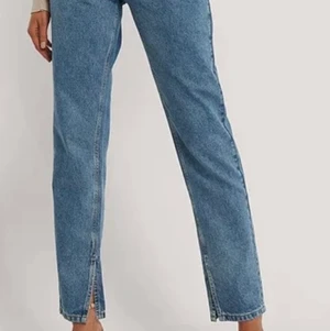 Raka jeans med hög midja - Jeans med slits från NA-KD i strl 40. Snygg rak passform och hög midja. Färgen ser ut som sista bilden. Sparsamt använda. Köparen står för fraktkostnaden. 