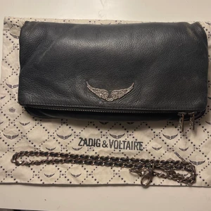 Zadig väska - Säljer min fina zadig väska i modellen ROCK, köpt på zalando med nypris på ca 3700. Väskan är använd men i bra skick endast sliten vid ”hörnen”. Det långa bandet saknas tyvärr, den är köpt på zalando så tror jag har ett digitalt kvit
