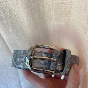 Grått skärp i ”ormskinn” material - Asläckert grått skärp i fake ormskinnmaterial. Bra skick 🤍 