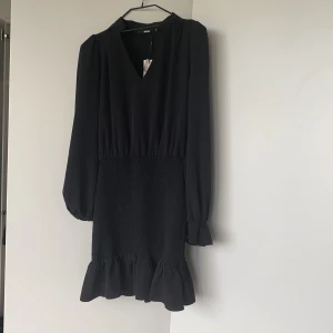 Smock Klänning Bikbok  - Svart klänning med smock och volanger. Storlek S BIKBOK