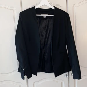 Svart kavaj i storlek 38 - Svart kavaj från H&M i storlek 38. Liten i storleken, inte oversized. Snygg detalj längst ner på båda armarna. Använd 2 ggr, inga täcken på användning, ser ut som ny.